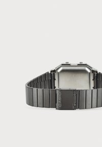 Négyzet alakú ezüst steak rozsdamentes acél házas kvarc karóra, fekete fém lánccal, amelyen a "CASIO" felirattal ellátott csat található.