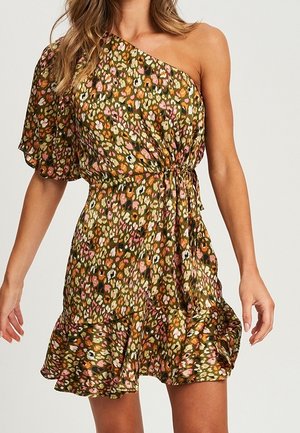 Kvinde iført en asymmetrisk, kort blomsterkjole med flæsekant og snørret talje i farverne olivengrøn, lyserød, orange og hvid.