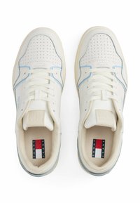 Witte en lichtblauwe sneakers met een geperforeerde bovenkant, veters en een rubberen zool. Heeft een textiel label met "TOMMY JEANS" op de inlegzool.