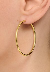 Orecchino a cerchio in oro, forma circolare, superficie liscia, finitura lucida, grandezza grande, leggero, indossato nel lobo dell'orecchio, accenti minimi.