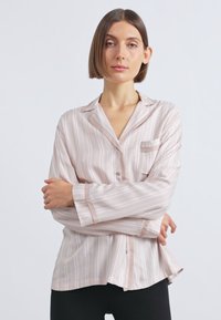 Svijetlo ružičasta pidžama košulja s okomitim bijelim prugama, kopča s gumbima sprijeda, ovratnik s urezima i jednim džepom, izrađena od glatke tkanine.