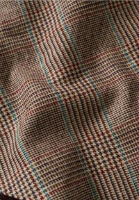 Tissu tissé avec un motif à carreaux dans des nuances de marron, bordeaux et bleu. Fini texturé avec un drapé doux et souple.