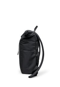 Sac à dos noir vu de côté avec une poignée supérieure, des bretelles réglables et une poche latérale zippée sur un fond blanc.