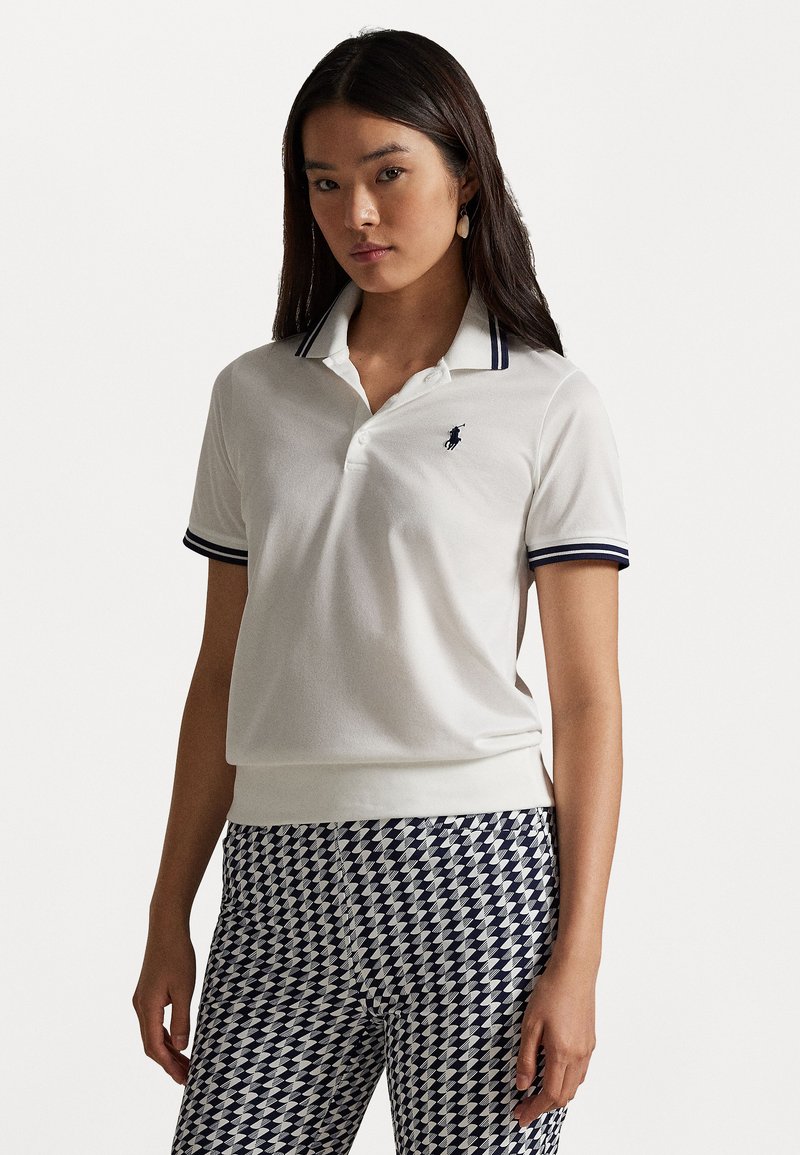 Biela polo košeľa s námorníckymi prúžkami na golieri a malým emblémom. Má krátke rukávy a rebrovaný lem. Je spárovaná s vzorovanými nohavicami.