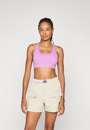 Lilla ermeløs crop-top med firkantet utringning, kombinert med lysebeige cargo-shorts som har to sidelommer og belte.
