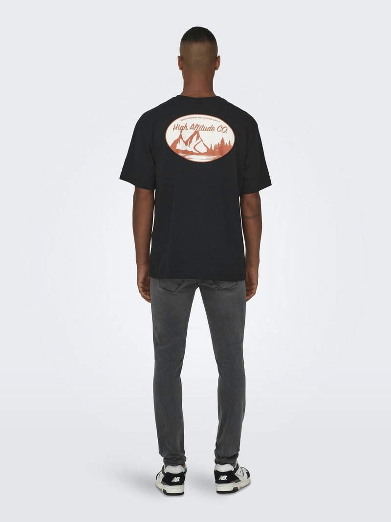 Zwarte katoenen T-shirt met korte mouwen, met een grote oranje grafiek van bergen en bomen op de achterkant. Gecombineerd met grijze jeans.