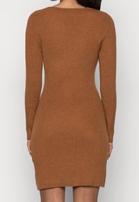 Vestido de punto acanalado en un cálido color marrón, con una silueta ajustada y mangas largas, escote redondeado y longitud hasta el muslo.