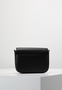 Borsa a tracolla in finta pelle nera con forma arrotondata, chiusura a pattina e texture a grana visibile. Presenta un design minimalista e hardware dorato.
