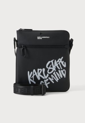 Czarna torba na ramię z przednim zamkiem i paskiem, zdobiona białym graffiti "Karl State of Mind" oraz logo "Karl Lagerfeld Jeans".