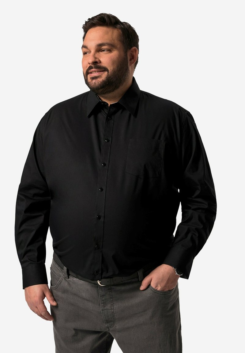 Camicia nera a maniche lunghe con bottoni e colletto, caratterizzata da una tasca sul petto e una texture liscia, abbinata a pantaloni grigi.