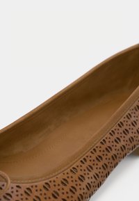 Καφέ δερμάτινο παπούτσι με επίπεδη σόλα, που διαθέτει διάτρητο σχέδιο, λείο εσωτερικό και στρογγυλή μύτη.