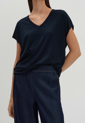Marineblaues V-Neck T-Shirt aus weichem Stoff, mit kurzen Ärmeln und lässiger Passform, kombiniert mit dunkelblauen Jeans.