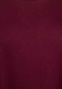 Bordo pamučni pulover s glatkom teksturom i klasičnim okruglim izrezom. Ima mekan, ravnomjeran pleteni uzorak kroz cijeli pulover.