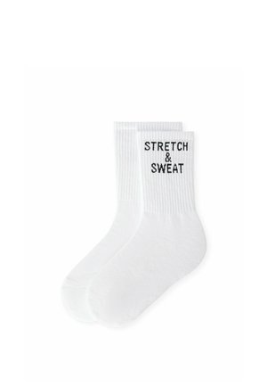 Paire de chaussettes blanches montantes à bord-côtes, avec un texte noir "STRETCH & SWEAT" sur la partie supérieure.