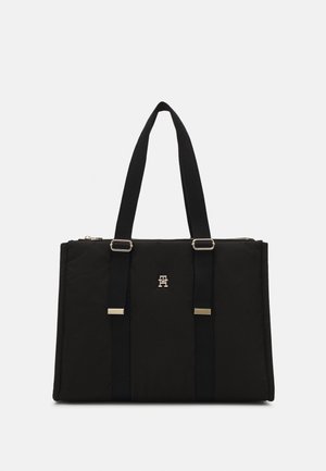 Sort rektangulær taske med to lange hanke, justerbare stropdetaljer og et lille metallisk logo midt foran.