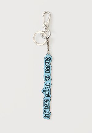 Portachiavi d'argento con un'etichetta blu appesa verticalmente, il testo dice "CHOOSE ME OR YOU LOSE ME" in lettere maiuscole nere.