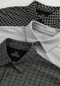 Camicie con colletto in grigio e due modelli neri; uno presenta piccoli quadrati, l'altro ha un motivo a griglia. Tutte hanno una vestibilità regolare e chiusura a bottoni.