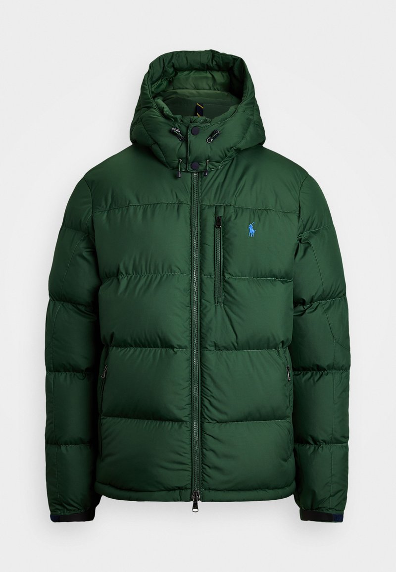Donkergroene pufferjack met een hoge kraag en afneembare capuchon. Voorzien van zwarte ritszakken en een klein blauw logo op de borst.