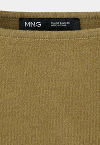 Gros plan sur l'encolure d'un vêtement en maille vert olive avec une étiquette noire indiquant MNG, taille EU-USA S/MEX CH, fabriqué en Chine.
