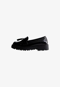 Mocasines de charol negro con suela gruesa, que presentan un borlas decorativa y un diseño elegante, mostrando un acabado suave y brillante.
