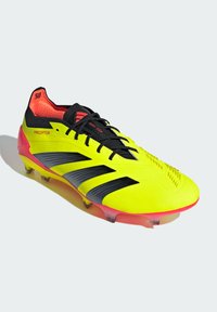 Scarpa da calcio neon gialla con strisce e dettagli neri, tomaia in sintetico texturizzato, suola rosa e punta rinforzata per stabilità.