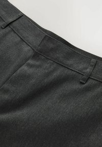 Pantalon sur mesure gris foncé avec une ceinture munie de passants et un devant lisse et épuré sans attaches visibles.