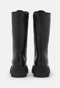 Stivali alti neri in pelle con finitura liscia, colletto imbottito e suola in gomma testurizzata. Presentano doppie cerniere laterali e dettagli di cucitura verticale.
