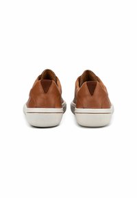 Braune Leder Sneakers mit glatter Textur und kontrastierender weißer Gummisohle. Sie verfügen über ein niedriges Profil und eine schmale Ferse.