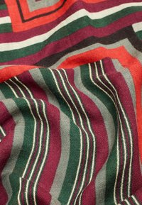 Multicolored textile featuring bold stripes in red, green, burgundy, and gray with thin white accents, displaying a soft, textured surface.