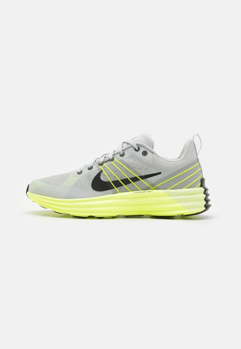 Chaussure de course Nike gris clair avec semelle jaune vif, logo swoosh noir et lignes d'accent jaunes sur le côté.
