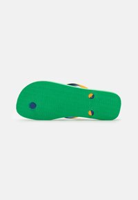 Green rubber outsole with textured grip, featuring blue and yellow accent dots. No visible brand markings or patterns.