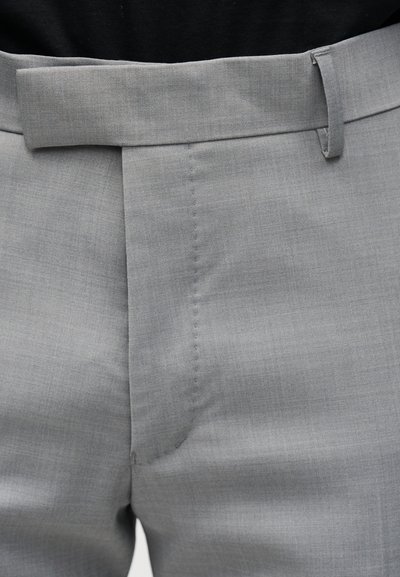 Κοντινή λήψη ανοιχτό γκρίζου, ραμμένου παντελονιού που δείχνει τη μέση, τη θηλιά της ζώνης και τη λεπτομέρεια της μπροστινής ραφής.