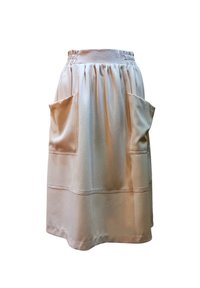 Falda beige hasta la rodilla con cinturilla elástica, dos grandes bolsillos frontales y diseño con pliegues. Textura suave con detalles cosidos.