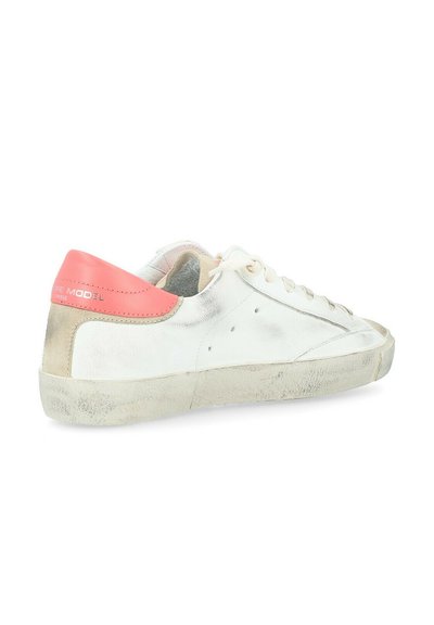 Baskets en cuir blanc avec un talon rose, des lacets blancs et une semelle en caoutchouc usée. Possède une finition métallique et de subtiles perforations sur les côtés.