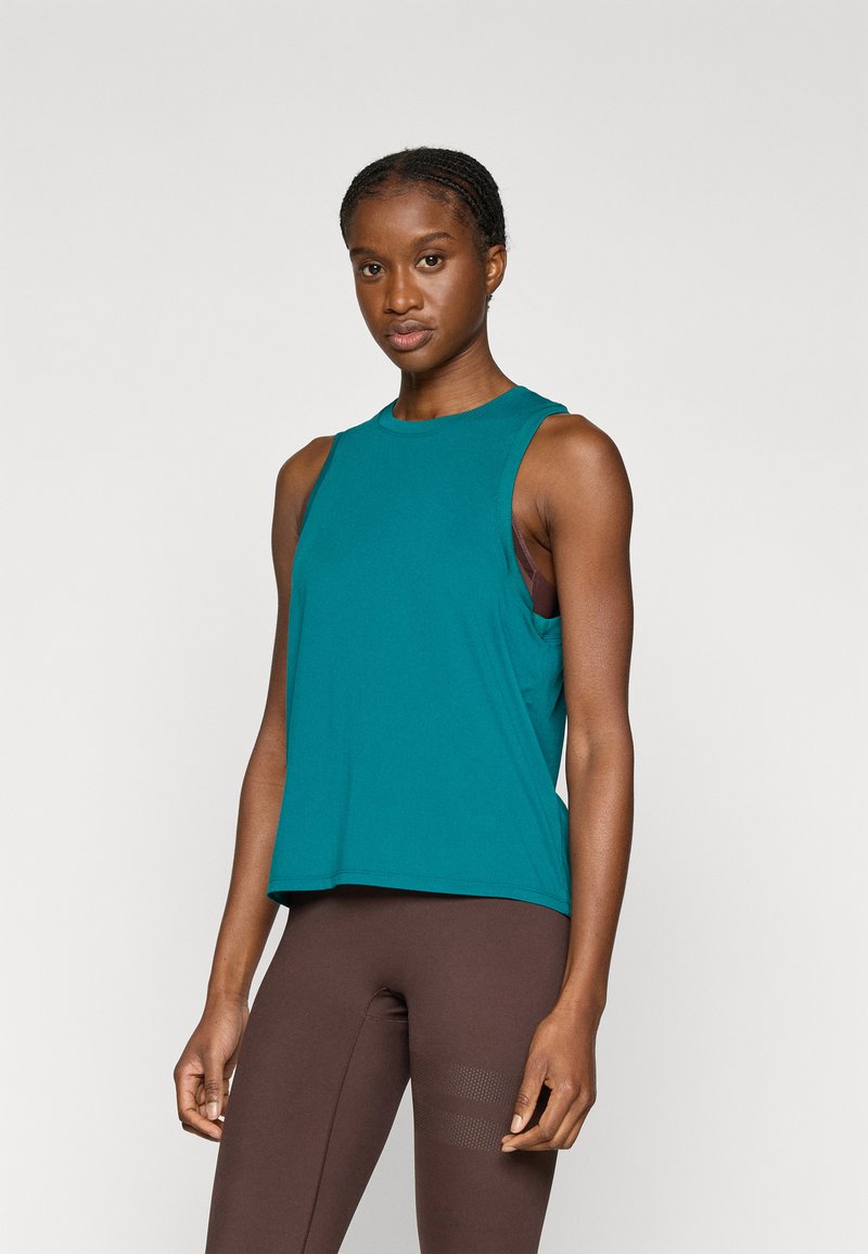 Αθλητικό τοπ σε τυρκουάζ χρώμα χωρίς μανίκια με στρογγυλή λαιμόκοψη. Μαλακό ύφασμα, χαλαρή εφαρμογή, με σχεδίαση σε στρώσεις πάνω σε καφέ βάση.