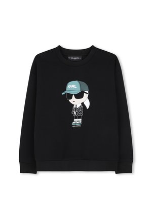 Sweat-shirt noir avec un personnage de dessin animé portant une casquette bleu sarcelle étiquetée "KARL,", des lunettes de soleil noires, une veste à motifs et des baskets au centre devant.