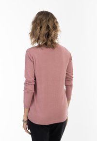 Lichtroze gebreide trui met lange mouwen, een ronde halslijn en geribde manchetten en zoom. Soepele textuur, eenvoudig ontwerp en aansluitende stijl.