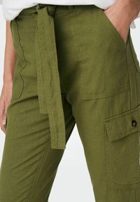 Olijfgroene cargobroek met een strikceintuur, gestructureerde stof, zijzakken en een knoopdetail op de zak. Aansluitend, middelhoge pasvorm.