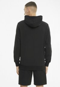 Svart hettegenser med snorhette, ribbede mansjetter og nederkant. Myk stoff, med jevn tekstur, brukt med matchende svarte shorts.