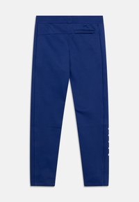 Pantalones deportivos azul marino hechos de una tela suave y elástica. Cuenta con un bolsillo trasero y un logo en el lado izquierdo. Textura lisa, diseño ajustado.