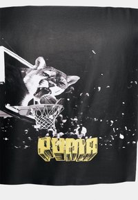 Sort stof med et grafisk motiv af et stort kattehoved nær en basketballkurv, med en bold og gule stiliserede tekster nederst.