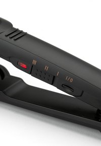 Piastra per capelli nera con interruttore di accensione, impostazioni di calore etichettate I, II, III e una spia rossa sul manico.