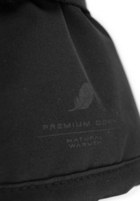 Borsa di stoffa nera con una texture liscia; include un logo stampato e un testo che recita "Calore Naturale Premium Down".