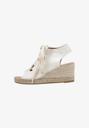 Sandalia cuña de cuero blanco con puntera abierta, suela de cuerda trenzada y cordones delanteros para atar.