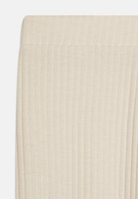 Beige rouné legíny s jemnou texturou a elastickým pasem, navržené pro pohodlné nošení a volnost pohybu.