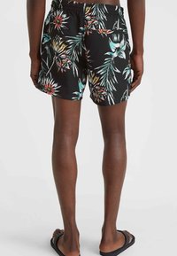 Bañador negro con un vibrante estampado floral que presenta hojas verdes y flores naranjas. Cintura elástica, longitud por encima de la rodilla y bolsillo trasero.