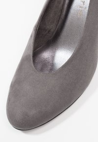 Chaussure à talon haut en daim gris avec un bout arrondi et un détail ajouré, dotée d'une semelle intérieure argentée brillante et d'un extérieur texturé mat.