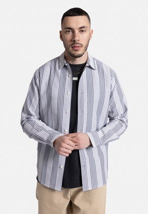 Striped button-up shirt in white and navy, made of lightweight fabric, featuring a spread collar and long sleeves with buttoned cuffs.