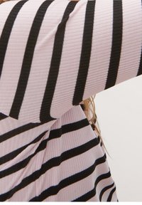 Top rosa con righe verticali nere e blu, in un tessuto ribbed texturizzato. Il capo presenta maniche lunghe e una vestibilità morbida.