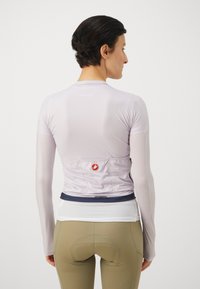 Light purple long-sleeve cycling jersey with a textured finish, featuring a white mesh back and a red logo at the waist.